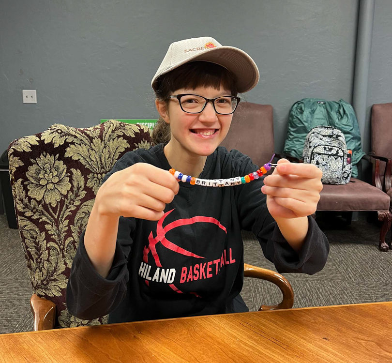 Brittany holding up a beaded string she made | Sacred Ground